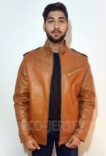A young man wearing a brown leather jacket with quilted shoulders and a zippered pocket, paired with a black shirt and blue jeans, standing in front of a white background.