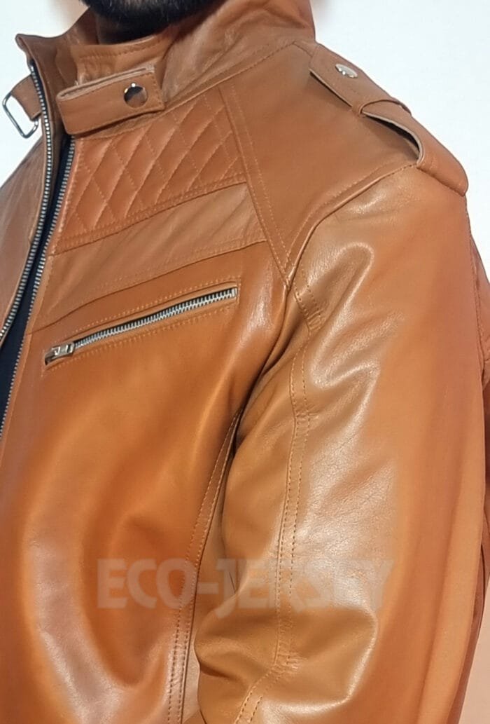 Detailed view of a full grain brown leather biker jacket featuring quilted shoulders and a zippered pocket.