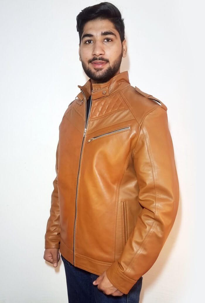 A young man wearing a brown leather jacket with a quilted design, black shirt, and blue jeans, standing against a white background.