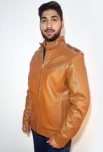 A young man wearing a brown leather jacket with a quilted design, black shirt, and blue jeans, standing against a white background.