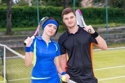 Cuple showing their sporst wear outfit in tennise court with their tennis rockets.