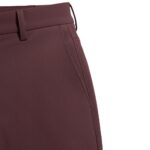 Close-up of wine-colored men's golf pants showing waistband, belt loops, and pocket opening.