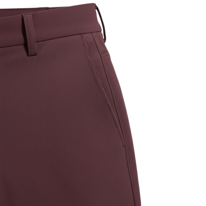 Close-up of wine-colored men's golf pants showing waistband, belt loops, and pocket opening.