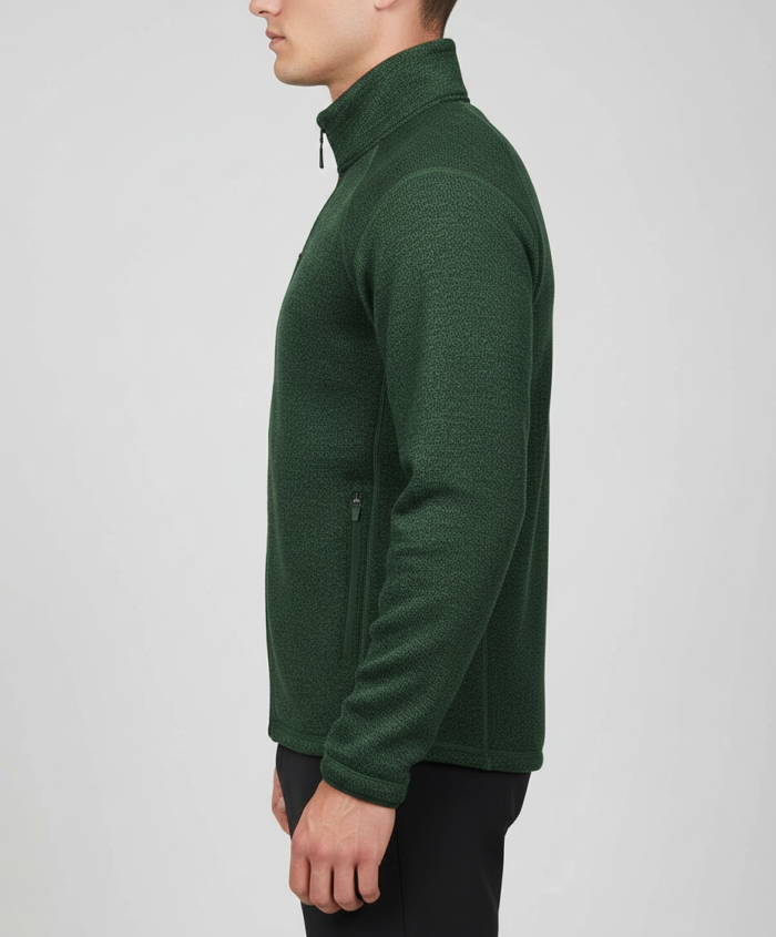 ide profile of a man wearing a dark green Zip-up golf fleece jacket and black pants against a light gray background.