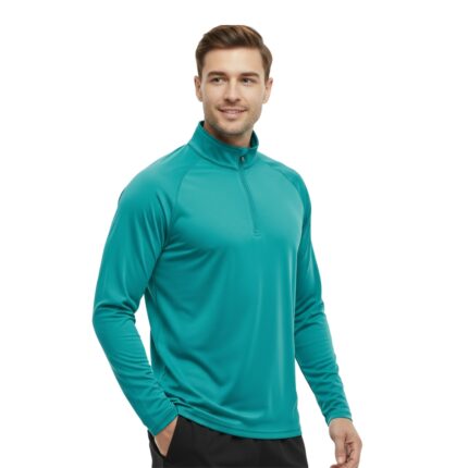 Man wearing teal long-sleeve golf quarter-zip shirt with black athletic pants, standing with one hand in pocket.