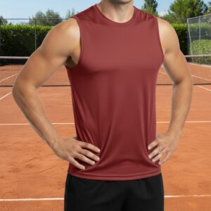 A man on a red clay tennis court stands with hands on hips, wearing a maroon sleeveless athletic shirt and black shorts, with a net, hedge, and trees in the background under a clear blue sky