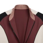 Close-up of a partially unzipped jacket showing burgundy center panels, cream and black shoulder panels, and a light brown ribbed collar.