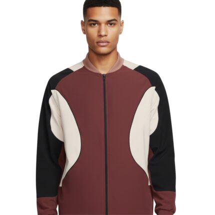 Man wearing a burgundy, cream, and black color-blocked bomber jacket with a zip front and light brown collar, photographed in a studio.