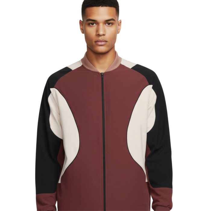 Man wearing a burgundy, cream, and black color-blocked bomber jacket with a zip front and light brown collar, photographed in a studio.