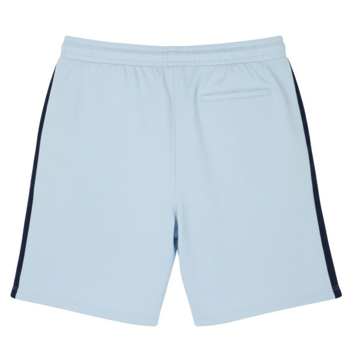 Light blue tennis shorts shown from the back with a dark blue stripe down each side, an elastic waistband, and a small back pocket on the right. The fabric looks smooth and athletic
