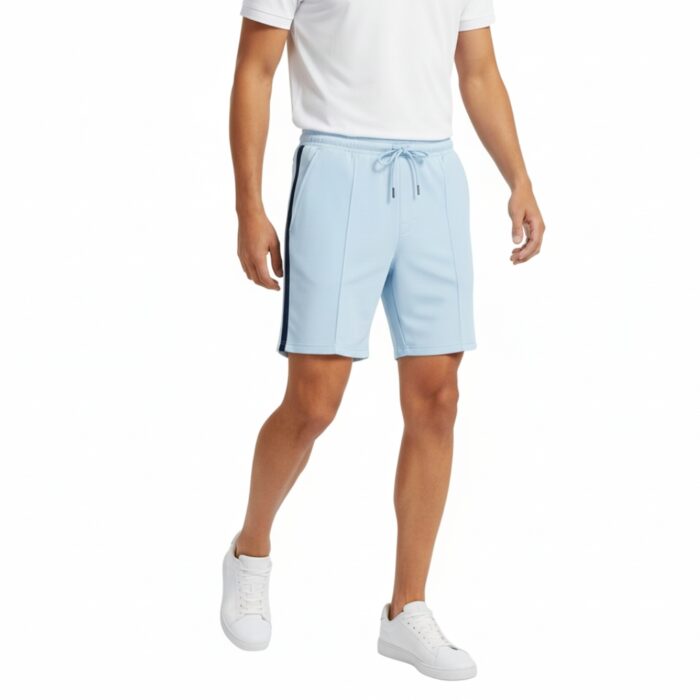 A man wearing a white t-shirt and light sky-blue tennis shorts with a navy side stripe, white sneakers, and a drawstring waist, walking forward with one foot raised. The background is plain white.