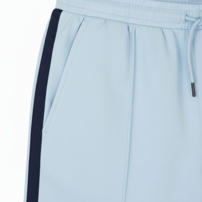 Close-up of light blue athletic shorts showing a dark blue side stripe, a drawstring at the waistband, and a side pocket.