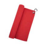 A red waffle-weave golf towel, partially rolled up, with a metal grommet and black carabiner in the top-right corner.