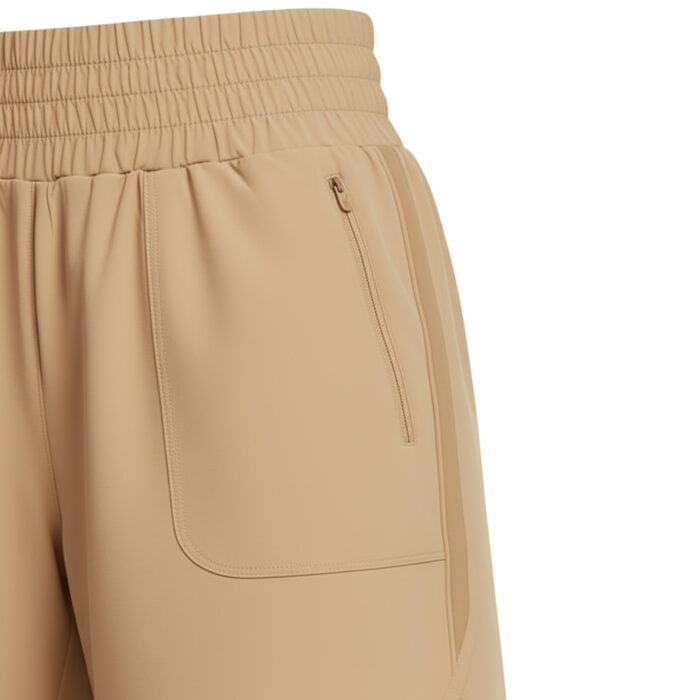 Close-up side view of tan women's tennis shorts with an elastic gathered waistband, a zip pocket on the right, a subtle side stripe, and a curved hem with a small side slit