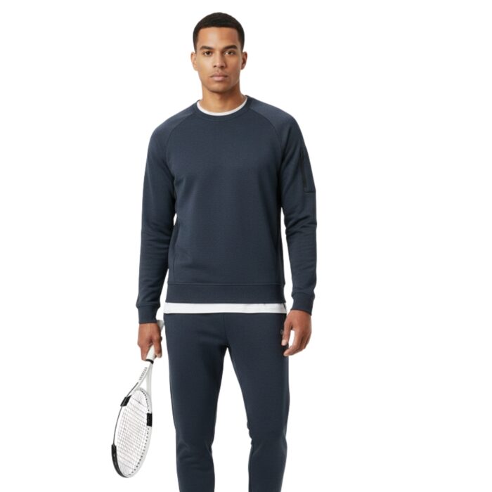 Full-body shot of a male model wearing a dark blue matching tennis sweatsuit, holding a white tennis racket in the left hand; white shoes