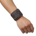 Close-up of a dark gray basketball wristband sleeve on a forearm featuring orange geometric stitching, photographed on a white background.