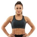 Person wearing a black sports bra with blue geometric patterns, posing with hands on hips.