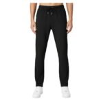 Front view of a person wearing black jogger pants with an elastic waistband, black drawstring, and white sneakers.