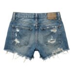 Back view of distressed blue denim shorts with frayed hems, visible rips, two back pockets, and a leather brand patch on the waistband.