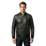 Man wearing a zipped-up black leather bomber jacket with ribbed collar and cuffs, paired with dark jeans, on a white background.