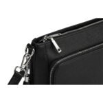Close-up of a black leather crossbody mini bag showing detailed zippers, detachable strap clips, and textured leather.