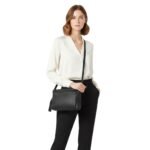 Woman wearing a white blouse and black pants, styled with a black leather crossbody mini bag.