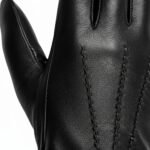 Closeup of black leather gloves with textured finish and stitched seams, shown against a white background.