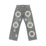 Front flat-lay of women's gray denim tear pants with white circle floral embroidery, grid patterns, and geometric ankle designs on a white background.
