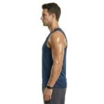 Side view of a man wearing a gym tank top and shorts, standing in a studio with a plain background.