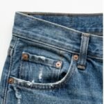 Closeup of denim jean short fabric texture with visible stitching and button hardware