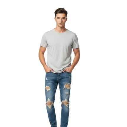 Man in gray t-shirt and ripped blue jeans standing on white background, hands in pockets.