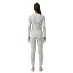 Back view of a woman wearing a light grey seamless ski base layer set with long-sleeve top and leggings, standing against a white background.