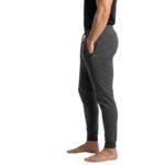 Side view of a man wearing tapered joggers and sneakers, standing against a white background.