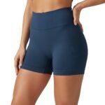 Front view of a woman wearing high-waisted black yoga shorts and sports bra, standing in a relaxed pose