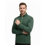 Man wearing a dark green performance golf quarter‑zip top on the course, with a stand collar, half zipper, long sleeves, and a small logo icon on the left chest.