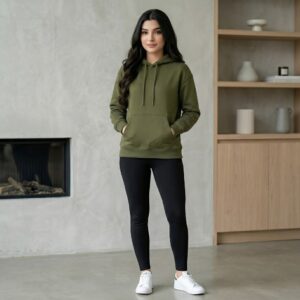 Female model wearing custom olive green classic pullover hoodie with black leggings in interior setting – custom casual apparel