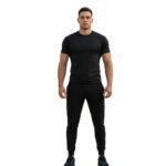 Model wearing soccer training joggers, standing to show the elastic waistband, tapered legs with cuffed ankles, and contrast side stripes with a logo icon.