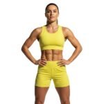 Model wearing women’s soccer shorts, standing to show the mid-rise elastic waistband, relaxed athletic fit, and bold logo icon on the leg.