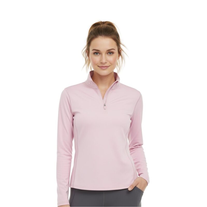 Woman wearing a pink lightweight golf quarter‑zip top on the course, with a stand collar, half zipper, long sleeves, and a small logo icon on the left chest.