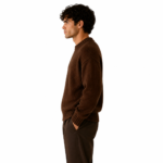 Side view of a male model wearing a dark brown chunky crew-neck knit pullover sweater on a white background showing side silhouette and knitwear texture
