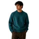Front view of a male model wearing a teal blue-green chunky crew-neck knit pullover sweater on a white background showing the colour option for the brown knitted sweater product