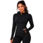 Female model wearing a custom black compression hoodie by Eco Jersey, featuring a full-zip front, fitted athletic silhouette, thumb holes, side pockets, and attached hood, paired with black leggings for a monochrome athletic look