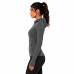 Side profile view of a female model wearing a custom gray compression hoodie by Eco Jersey, showing the fitted athletic cut, attached hood, full-zip front, and flattering body-contouring silhouette with black leggings