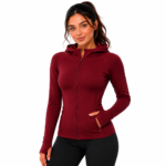 Female model wearing a custom red compression hoodie by Eco Jersey, featuring a full-zip front, fitted athletic silhouette, thumb holes, side pockets, and attached hood, paired with black leggings