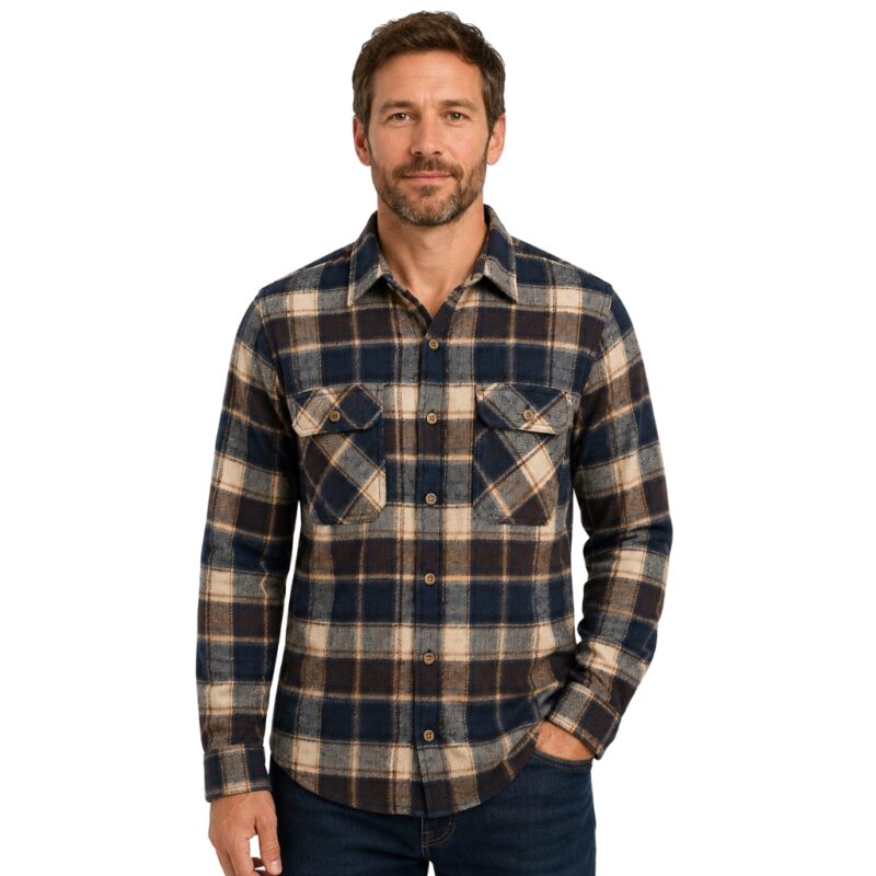 Smiling bearded man wearing a custom navy blue, brown, and cream plaid flannel shirt by Eco Jersey, paired with dark jeans, showcasing a casual and stylish everyday look