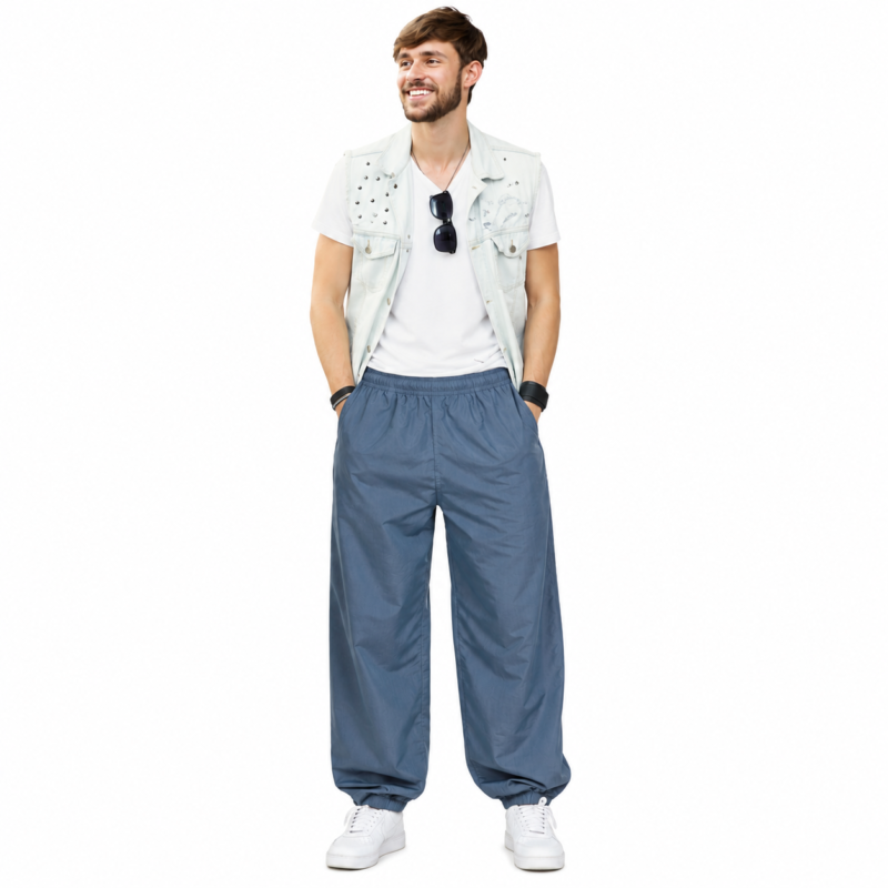 Smiling male model wearing custom blue pumper pants by Eco Jersey from the front, styled with a white t-shirt, denim vest, and white sneakers, showing the full balloon fit silhouette and elastic waistband