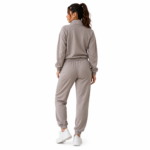 Back view of a female model wearing the super soft women's velour tracksuit in beige with zip-up mock-neck hoodie and tapered jogger sweatpants showing rear silhouette and fit