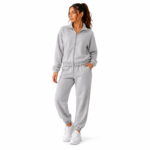 Female model wearing the super soft women's velour tracksuit in grey colour option with zip-up mock-neck hoodie and tapered jogger sweatpants for colour reference