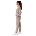 Side view of a female model wearing the super soft women's velour tracksuit in beige with zip-up mock-neck hoodie and tapered jogger sweatpants showing side silhouette and fit