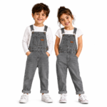 Smiling boy and girl wearing matching gray denim overalls with white long-sleeve tops and white sneakers on a clean white background